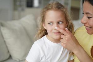 Smiling foster mom touching nose of adopted small daughter. Happy motherhood, adoption of children photo