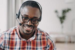 trabajador afroamericano sonriente del servicio de apoyo que lleva auriculares y gafas, retrato en la cabeza foto