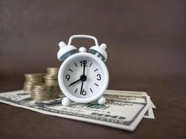 Alarm clock, coins and banknotes on a dark background. The idea of business, Finance concept and saving money and time photo