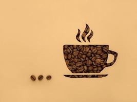 The symbol Is a Cup of black aromatic coffee beans. Paper background, cut out, with copy of the space and space for text photo