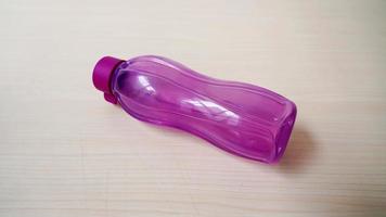 a purple water bottle on a wooden table photo