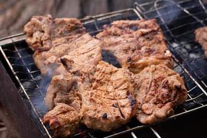 Beef steak on grill. Meat on coals with smoke photo