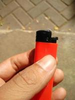 a gas lighter that is red or orange in the palm of the hand photo