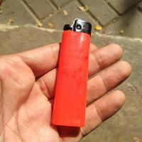 a gas lighter that is red or orange in the palm of the hand photo