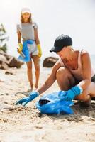 Mother And Daughter Collecting Trash On The Beach photo