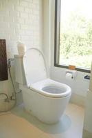 white toilet in restroom with window photo