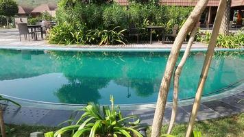 hermosa piscina azul en un caluroso día de verano con vegetación tropical y sombras. relax y ocio en asia resort. vacaciones en villa moderna en tailandia, phuket. villa privada de lujo con palmeras video
