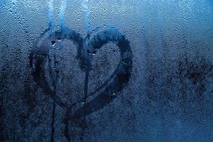 Heart painted on misted glass. Valentines day, love symbol on frozen glass in winter. photo