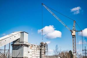 Tower crane against blue sky in old concrete factory. photo