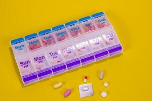 See Through Weekly Pill Box On Smooth Yellow Background photo