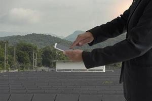 Man using a smartphone controlled  a solar panel with sky and mountains photo