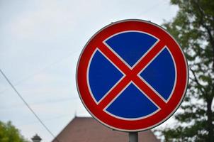 señal de tráfico redonda con una cruz roja sobre un fondo azul. una señal significa una prohibición de estacionamiento foto