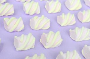 Colorful marshmallow laid out on violet paper background. pastel creative textured pattern. Perspective macro shot photo