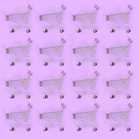 Shopping addiction, shopping lover or shopaholic concept. Many small empty shopping carts perform a pattern on a pastel colored paper background. Flat lay composition, top view photo