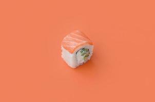 rollo filadelfia con salmón sobre fondo naranja. minimalismo vista superior plana con comida japonesa foto