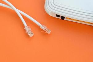 Internet router and Internet cable plugs lie on a bright orange background. Items required for Internet connection photo