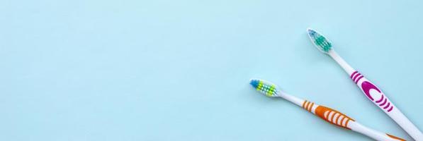 Two toothbrushes lie on a pastel blue background. Top view, flat lay. Minimal concept photo