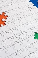 Close-up texture of a white jigsaw puzzle in assembled condition with missing elements, under which surfaces of different colors photo