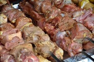 Raw meat and potatoes are planted on metal skewers. The process of cooking shish kebabs. Russian and Ukrainian camp food photo