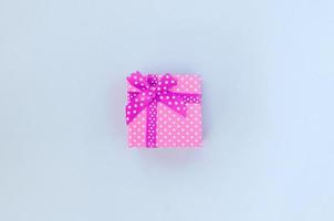 Small purple gift box with ribbon lies on a violet background photo