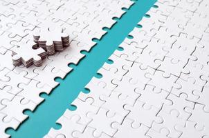 The blue path is laid on the platform of a white folded jigsaw puzzle. The missing elements of the puzzle are stacked nearby. Texture image with space for text photo