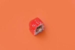 California Maki sushi roll with caviar on orange background. Minimalism top view flat lay with Japanese food photo