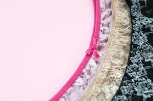ropa interior de mujer blanca, negra y rosa con encaje sobre fondo rosa con espacio para copiar. publicidad para tienda de ropa interior femenina hermosa y cómoda foto