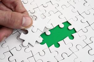 The human hand fills the last missing elements of the surface from the jigsaw puzzle. The concept of the completion of the initiated cases photo
