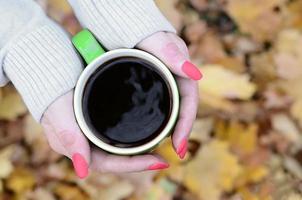 Woman wearing white sweater holding a green coffee cup photo