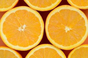 Top view of a several orange fruit slices on bright background in orange color. A saturated citrus texture image photo