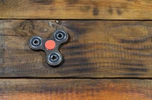 A rare handmade wooden fidget spinner lies on a brown wooden background surface. Trendy stress relieving toy photo