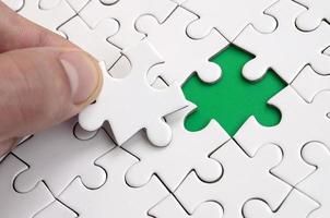 The human hand fills the last missing elements of the surface from the jigsaw puzzle. The concept of the completion of the initiated cases photo