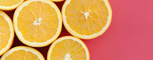 Top view of a several orange fruit slices on bright background in red color. A saturated citrus texture image photo