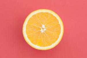 Top view of a one orange fruit slice on bright background in red color. A saturated citrus texture image photo