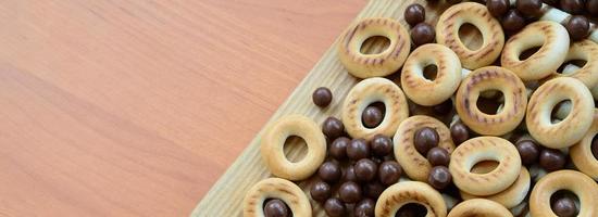 túbulos crujientes, bolas de chocolate y bagels yacen sobre una superficie de madera. mezcla de varios dulces foto