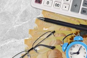 100 Canadian dollars bills and calculator with glasses and pen. Business loan or tax payment season concept. Time to pay taxes photo