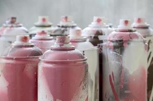 A lot of dirty and used aerosol cans of bright pink paint. Macro photograph with shallow depth of field. Selective focus on the spray nozzle photo