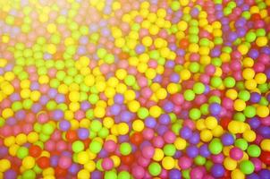 muchas bolas de plástico de colores en una piscina para niños en un parque infantil. patrón de primer plano foto