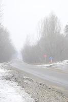 cruce de caminos en una carretera asfaltada suburbana en invierno durante una ventisca foto