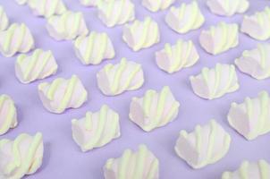 Colorful marshmallow laid out on violet paper background. pastel creative textured pattern. Perspective macro shot photo