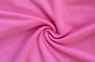 The blanket of furry pink fleece fabric. A background of light pink soft plush fleece material with a lot of relief folds photo
