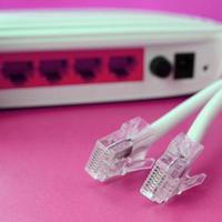 el enrutador de Internet y los enchufes del cable de Internet se encuentran sobre un fondo rosa brillante. elementos necesarios para internet foto