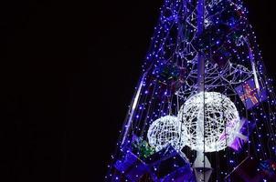 Fragment of the New Year tree. A lot of round lights of blue color are located on a conical frame photo