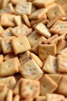 Background texture of small edible squares baked from dough and sprinkled with salt. A lot of salt cracker photo