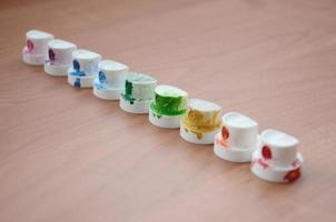 The soiled multicolored nozzles from the paint sprayer are lined up on a wooden table. Street art concept photo