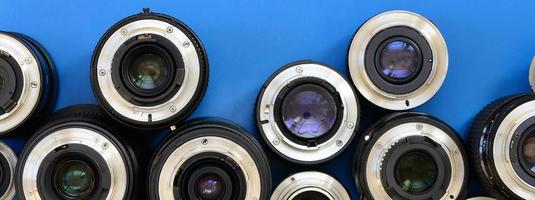 Several photographic lenses lie on a bright blue background. Space for text photo