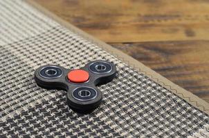 A rare wooden handmade spinner lies on a checkered plaid on a brown wooden background surface. Trendy stress relieving toy photo