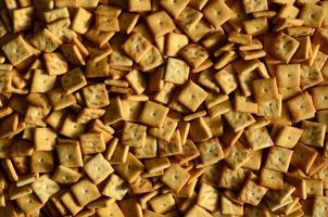Background texture of small edible squares baked from dough and sprinkled with salt. A lot of salt cracker photo