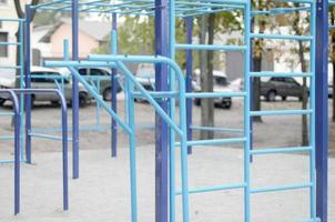 Sports bars in blue on the background of a street sports ground for training in athletics. Outdoor athletic gym equipment. Macro photo with selective focus and extremely blurred background