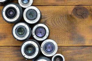 varias lentes fotográficas yacen sobre un fondo de madera marrón. espacio para texto foto